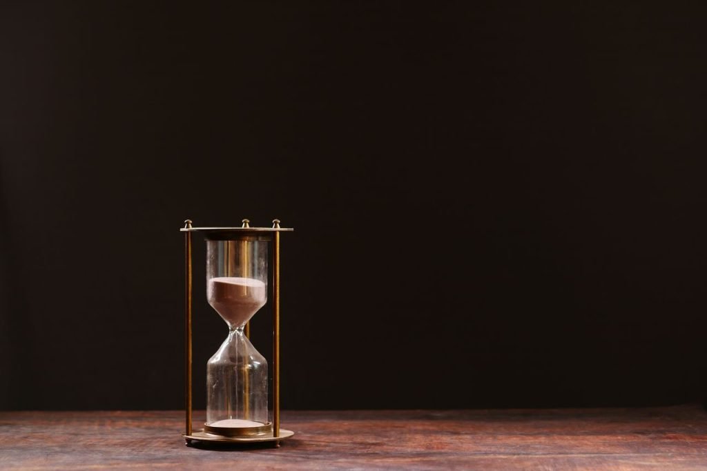 project management A classic hourglass with sand trickling down, symbolizing the passage of time, against a dark background.